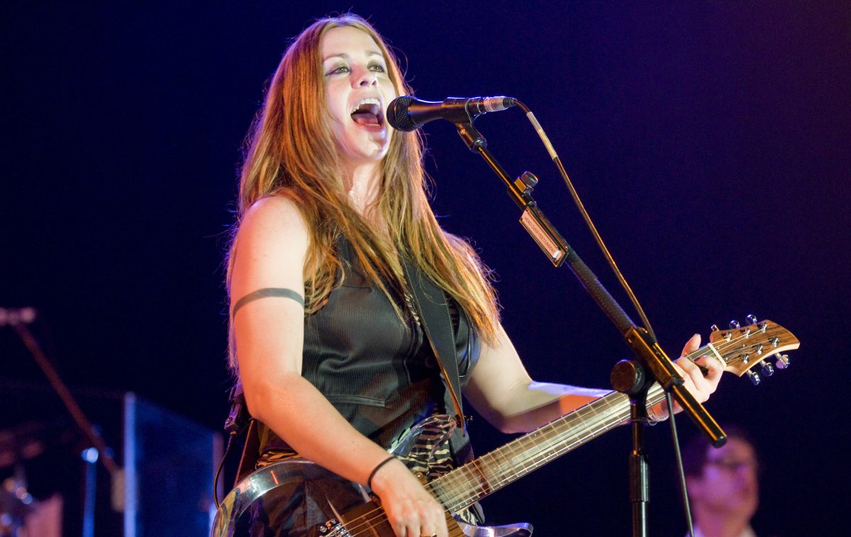Alanis Morissette cantando con su guitarra durante un concierto
