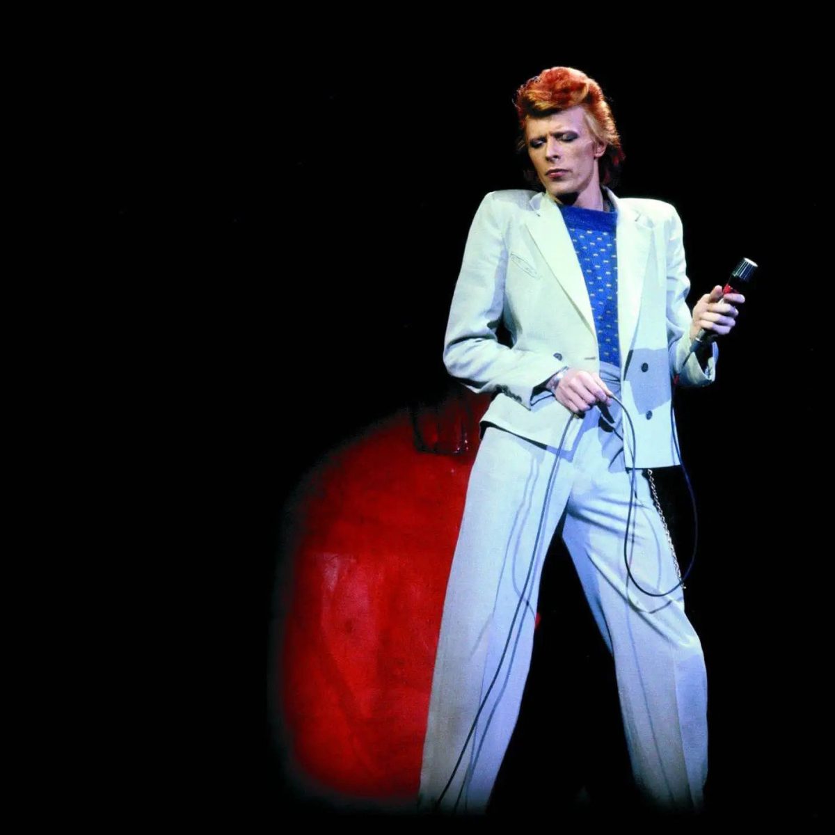 David Bowie, con traje claro y micrófono en la mano, en un concierto de 1974