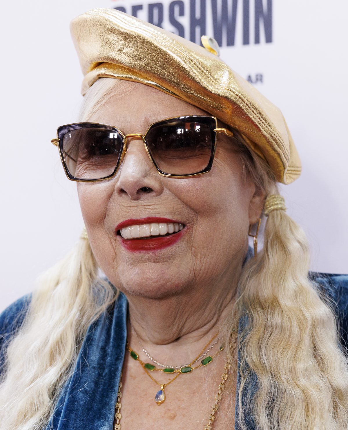 Joni Mitchell, sonriente con boina dorada y gafas de sol, en la alfombra roja del premio Gershwin de 2023
