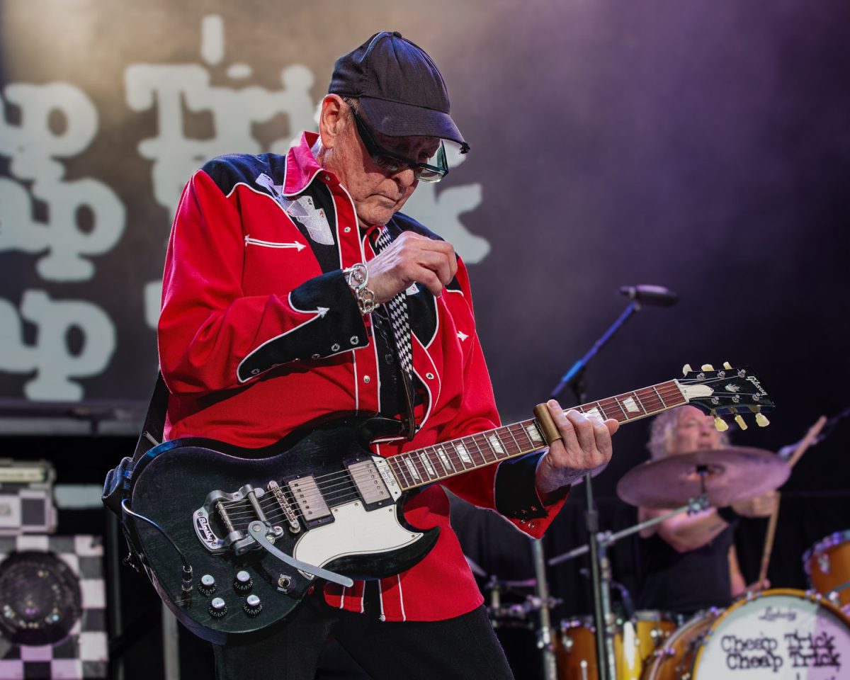 Rick Nielsen, guitarrista de Cheap Trick, con gorra y camisa roja en un concierto de 2025